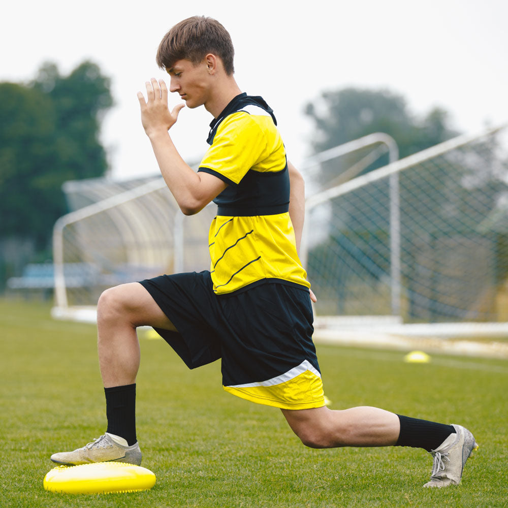 Teenage boy stretching before soccer game.